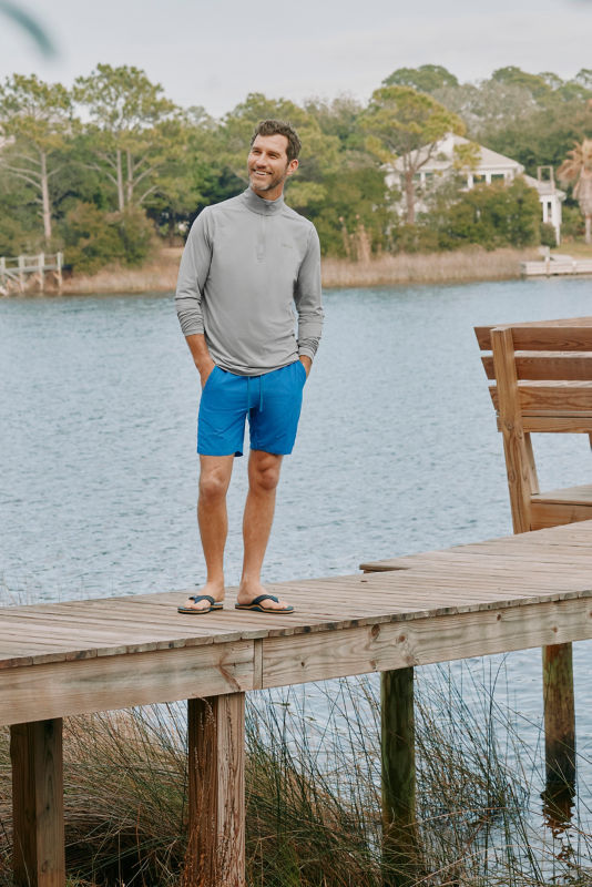 A model wearing bright blue shorts next to the water.