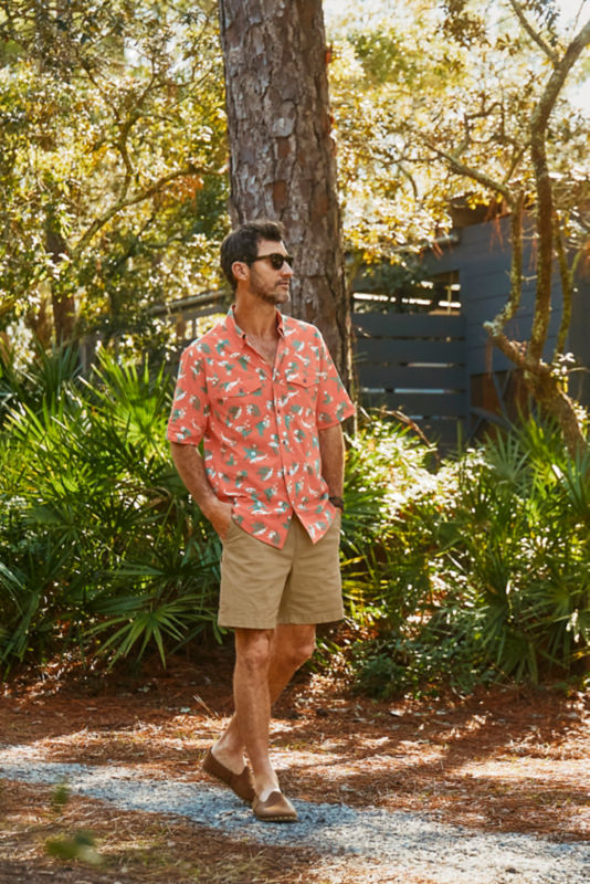 Man wearing red printed shirt and khaki shorts walking down a path.