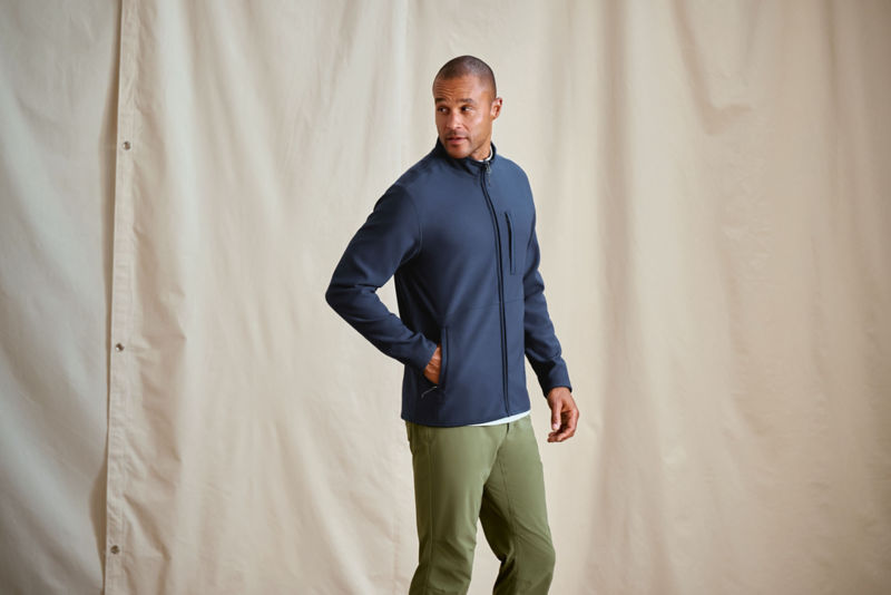 A man wearing a zip down fleece jacket poses in front of a white canvas background.