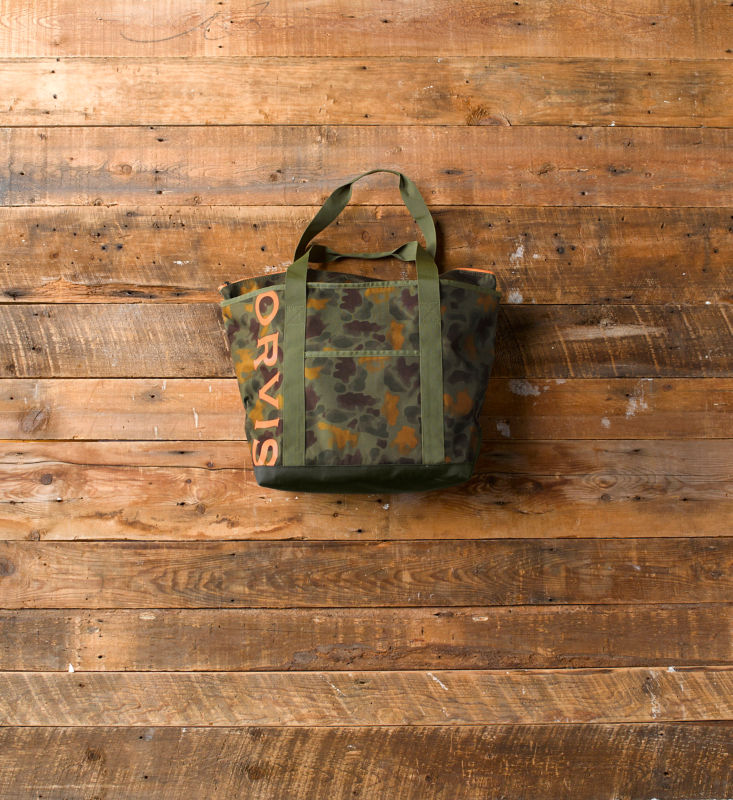 A camo tote bag laying on a wooden background.