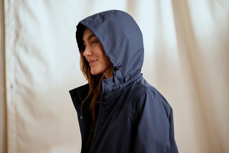 A model wearing a navy jacket with the hood pulled up over her head.