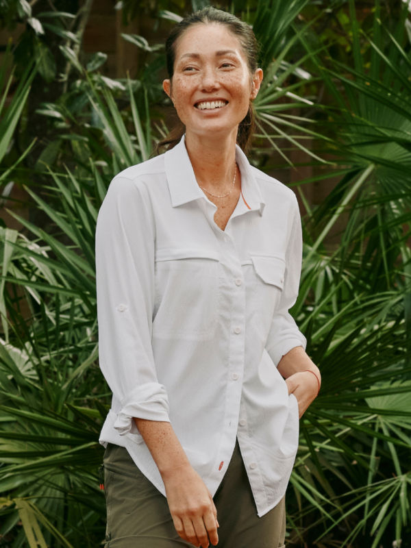 A smiling model wearing a white long-sleeve button-down tech shirt.