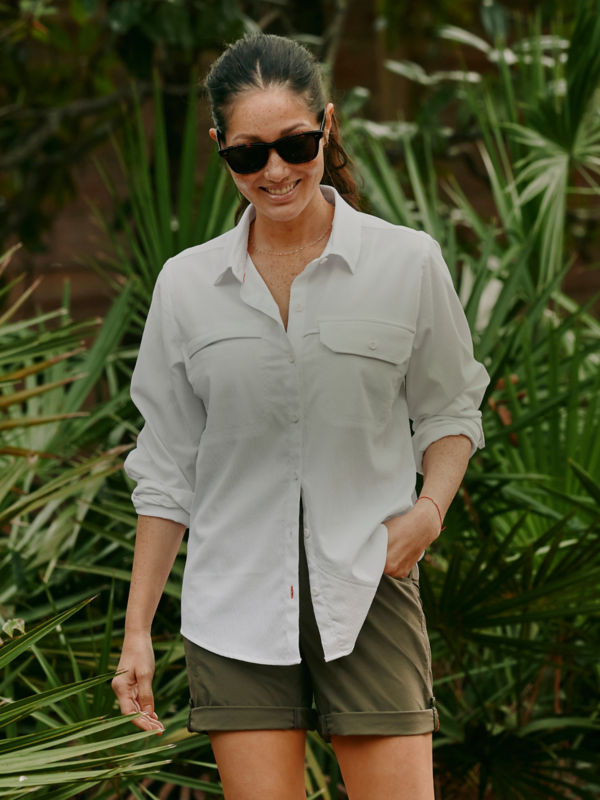 A smiling hiker with sunglasses pauses looking down