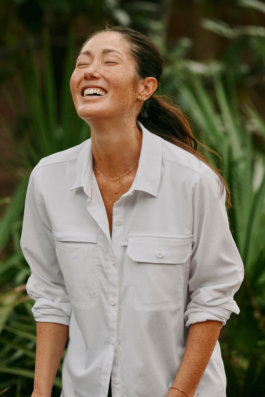A smiling woman wearing a white button-down shirt with UPF.