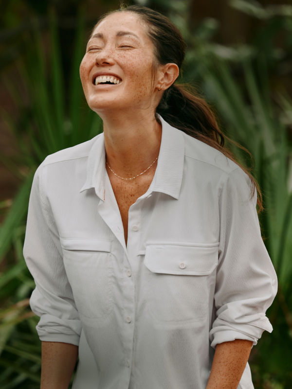 A smiling hiker wearing a white sun protective shirt.