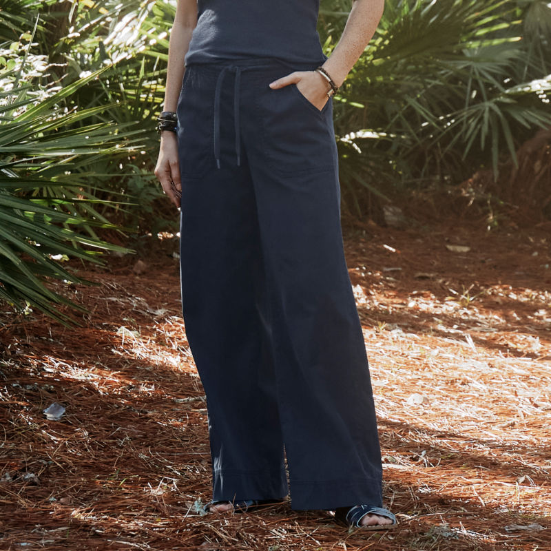 A model stands in a tropical forest while wearing comfortable navy pants with a navy tank.