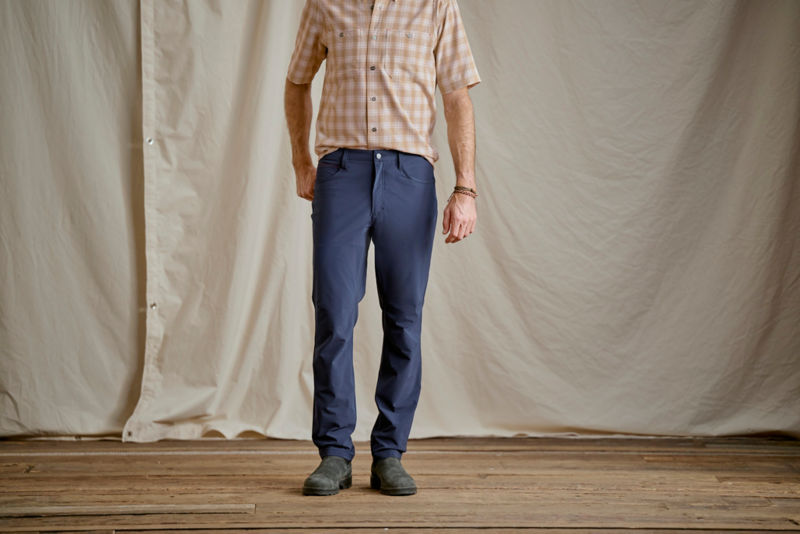 A waist-down view of a man wearing blue pants.