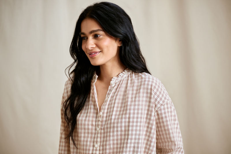 A woman wearing a red patterned button-down shirt.