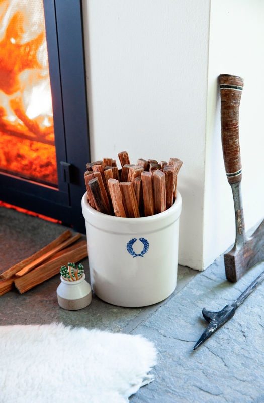 Fatwood on end fills a ceramic crock next to a fireplace.
