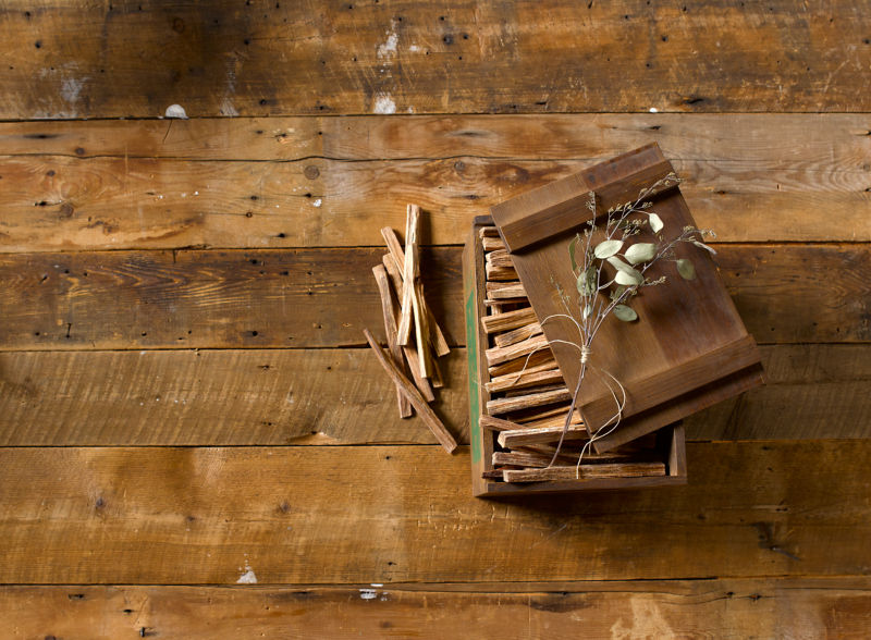 A wooden crate of fatwood sits open on a rugged barn floor.
