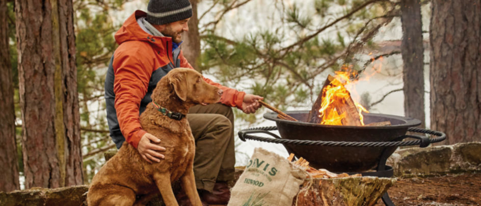 man with his dog starting a campfire with fatwood kindling