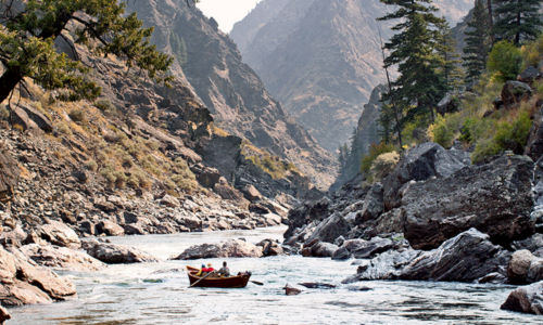 Anglers direct their boat into a rocky canyon.