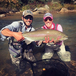 Two anglers excitedly holding up the large trout they caught.