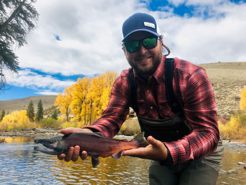 A smiling angler shows off a sweet fish on a fall day out west.