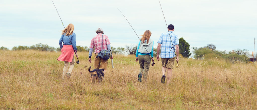 Four people and a dog walking through a field