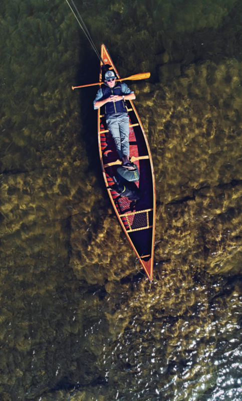 A drone view of an angler laying in a canoe.