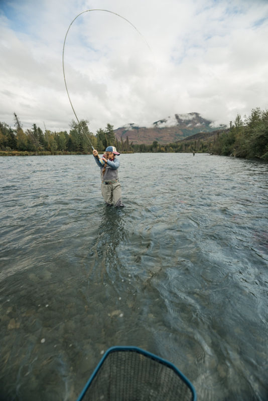 An angler sets her hook with a strong pull backwards on her fly rod.