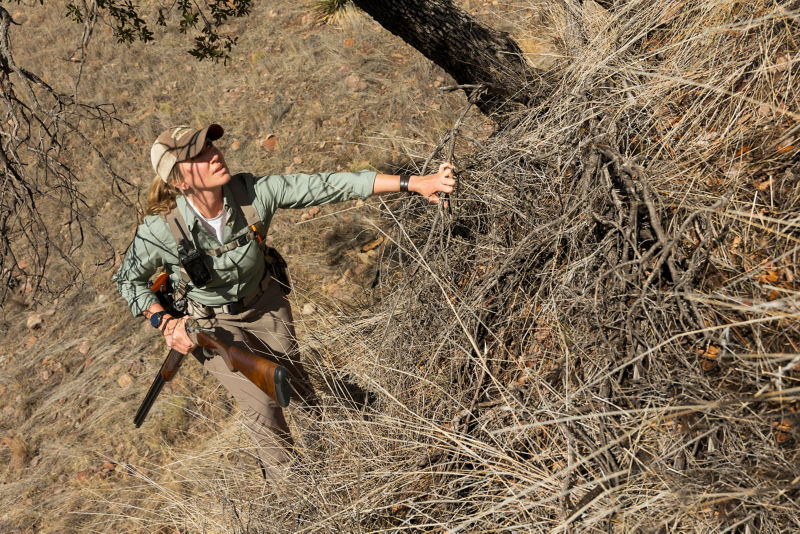 A hunter in a field under a big, bright sky.