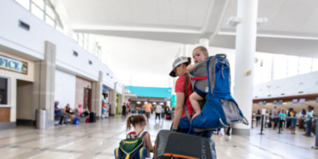 A woman walking through an airport with children and Orvis Luggage