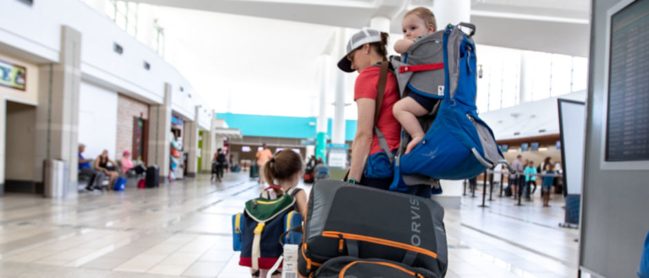 A woman and children walking with bags through an airport