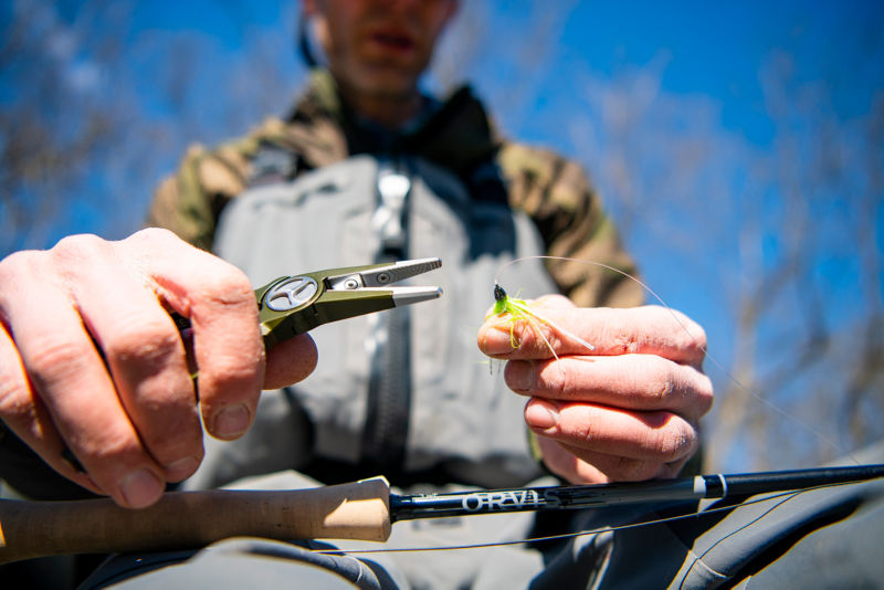 An Angler adjusts flies on his line with pliers.