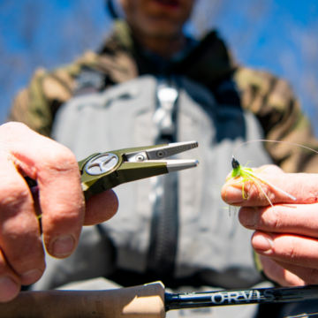 An Angler adjusts flies on his line with pliers.