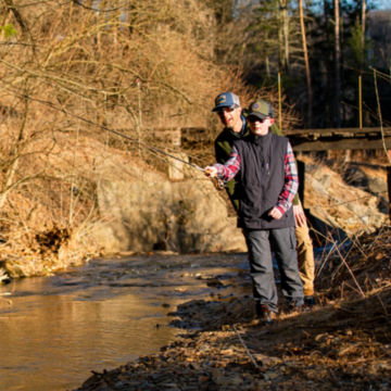 An angler and his son fish alongside a shallow river with an Encounter Rod.