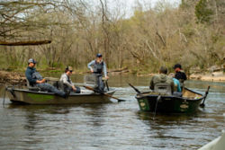 A group of anglers in two boats float in a river