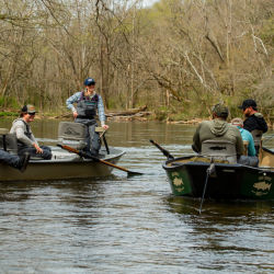 A group of anglers in two boats float in a river