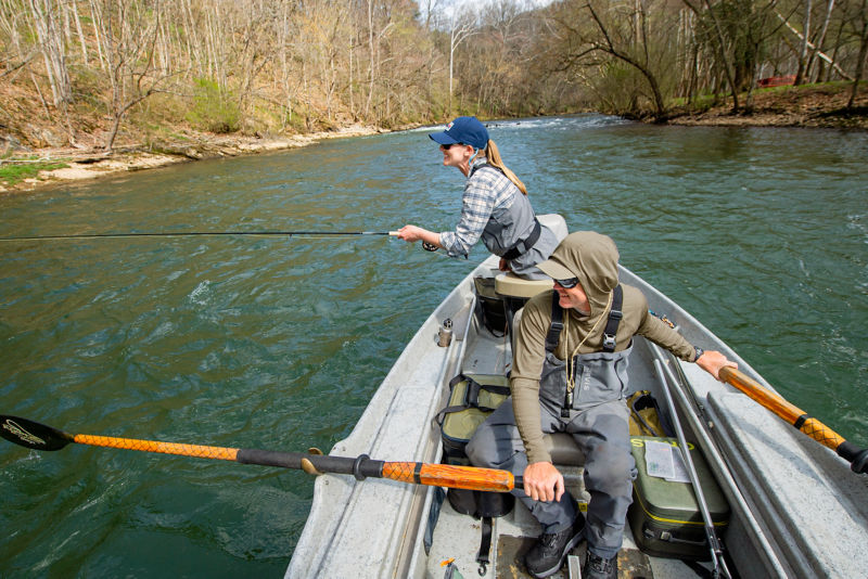 Two anglers in a row boat on a fast-moving river.