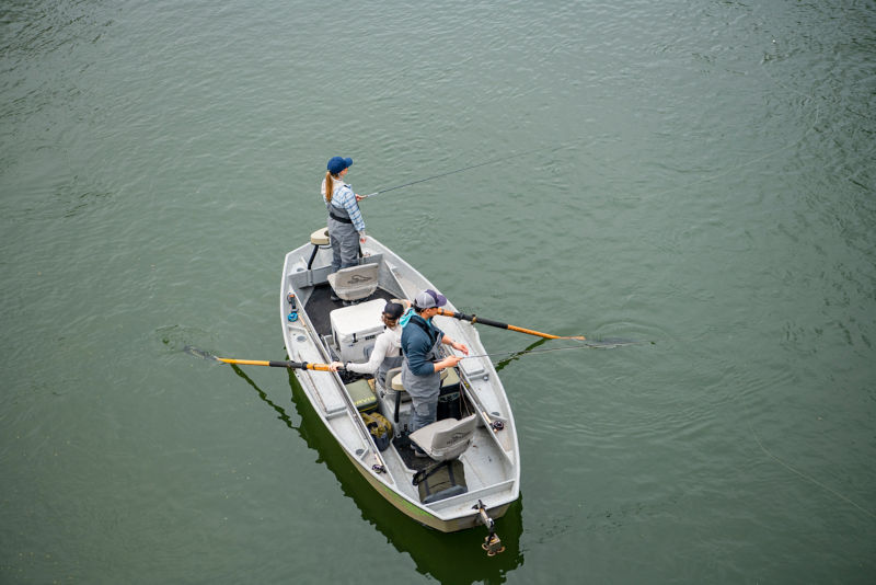 Three anglers in a boat on a river.