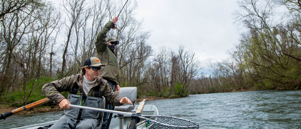 An angler lifts his H3 Blackout rod high in the air as his friend prepares the net.