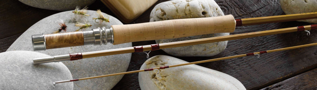 A bamboo fly rod resting on white rocks with some dry flies scattered around it