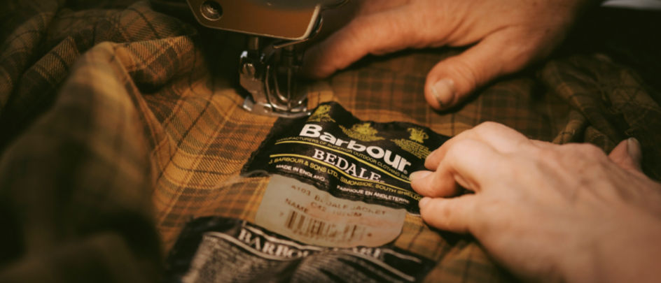Close-up of someone sewing the interior lining of a Barbour jacket.