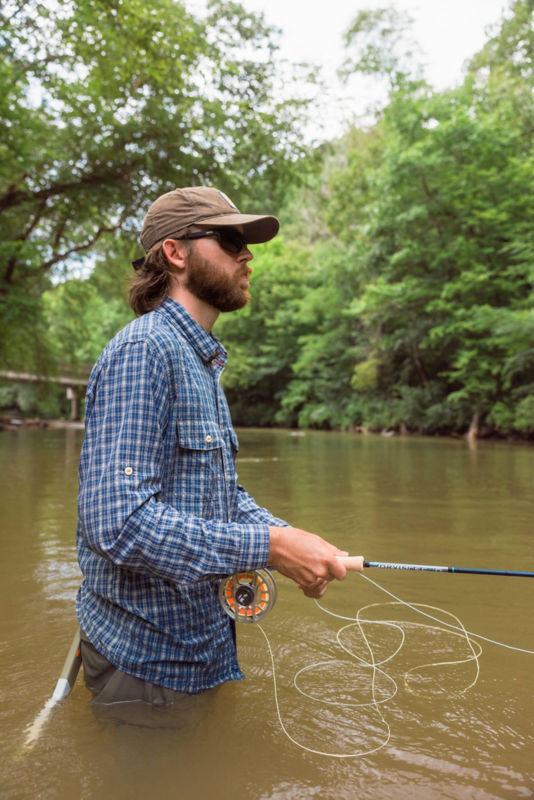 Line spools out as an angler wearing a blue plaid shirt concentrates on his quarry.
