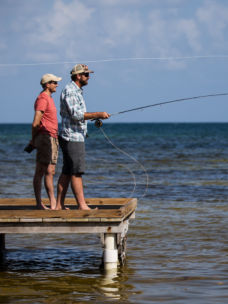Two anglers at the end of a pier fly fishing