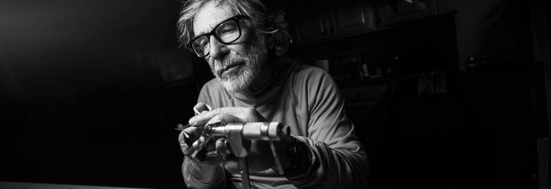 A black and white image of Tom Rosenbauer tying a fly.