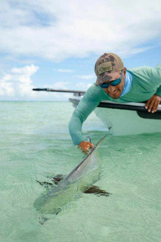 A man reaching into the water to release a fish in the Flats.
