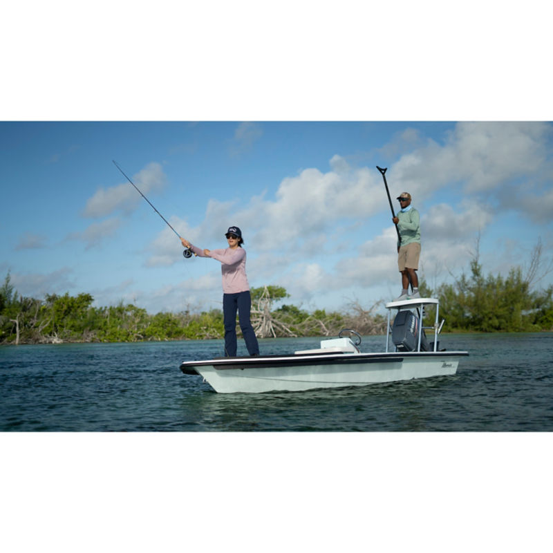 A woman fishing on a boat with a guide.