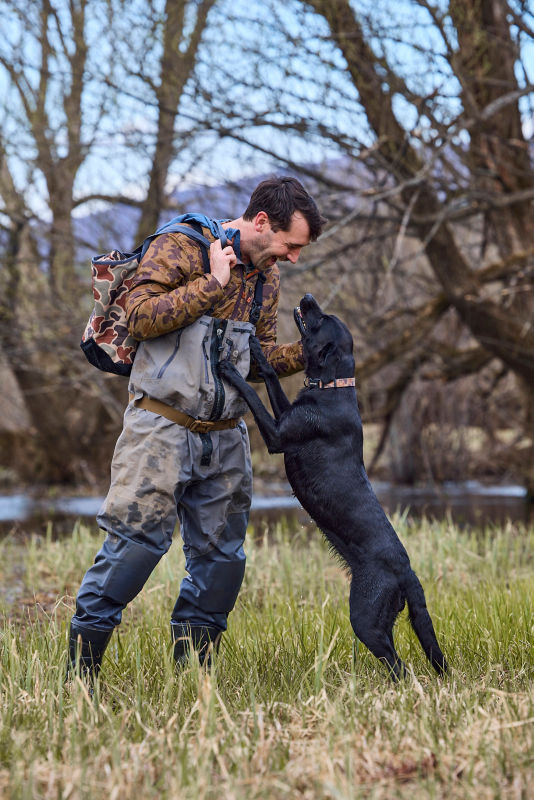 Charley pets Romi while wearing camo for duck hunting.