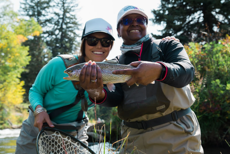 Two women triumphantly holding up a fish they caught.