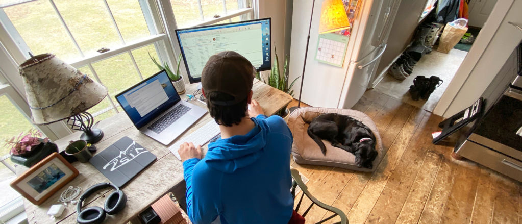 A Orvis employee at his desk in his home office with his dog asleep on a bolster dog bed