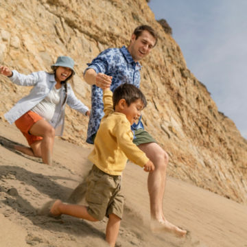Man in Tech Chambray 1971 Camo Long-Sleeved Shirt runs down a sand dune with his family.