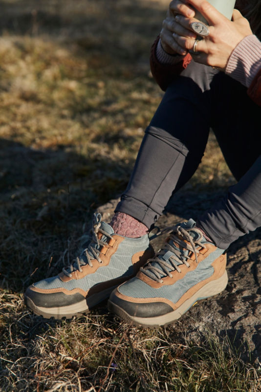 A close up of someone wearing hiking boots sitting on the ground.