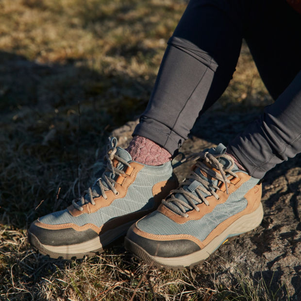 A close up of someone wearing hiking boots sitting on the ground
