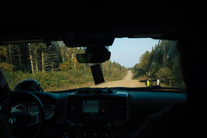 A view over the dash of a truck heading down a dirt road with rods in a rack up front.
