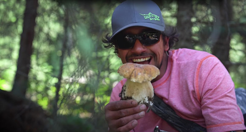 An excited man holding a foraged mushroom.