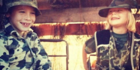 Charley and Hannah Perkins as children wearing camo-patterned clothes while sitting in a duck blind