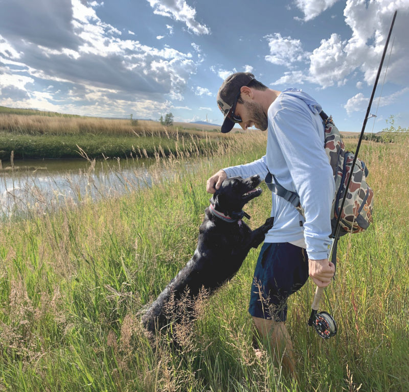 Charlie Perkins pets his black Labrador Romi at the riverside.