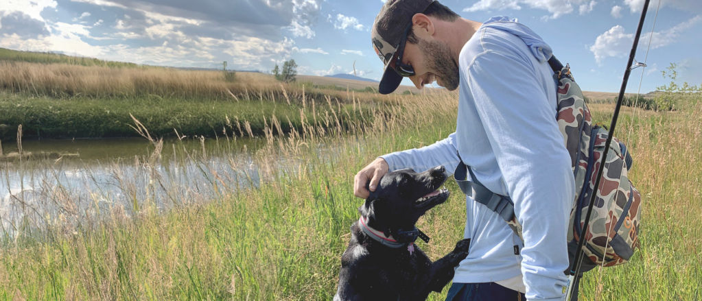 Charlie Perkins pets his black Labrador Romi at the riverside.